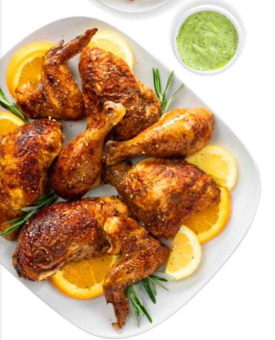 Rotisserie chicken pieces with orange slices, rosemary and a cup of green Boca Sauce